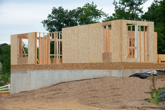 Chantier de construction résidentielle en cours, ossature bois en phase d'érection sur fondation béton