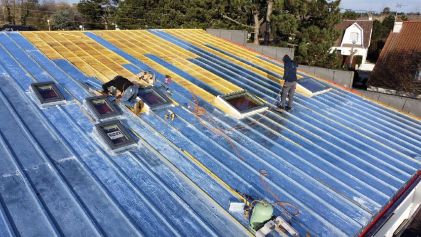 Ouvrier en &eacute;quipement de protection individuelle utilisant une scie circulaire pour d&eacute;couper une poutre en bois massif sur un chantier de construction