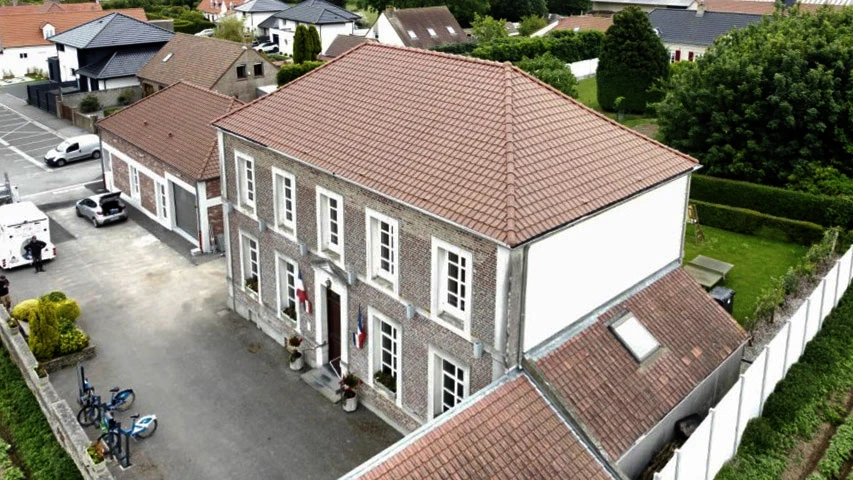 Ouvriers effectuant des travaux de couverture sur une maison moderne à deux étages avec bardage gris et blanc