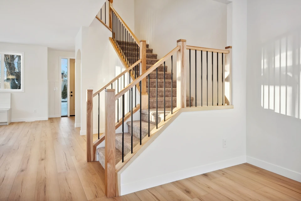 Une main masculine saisit fermement la main courante d'un escalier intérieur en bois