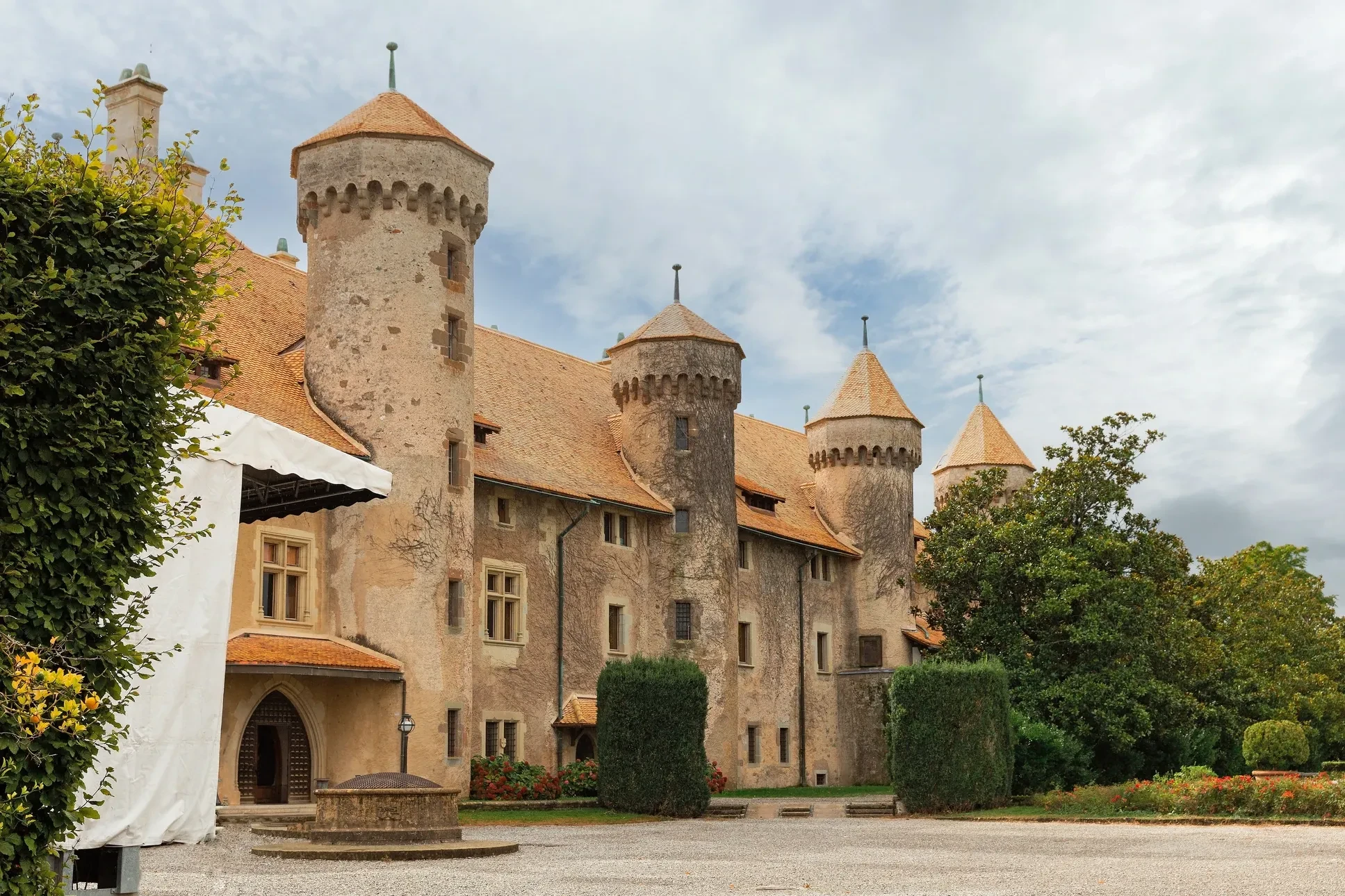 Château médiéval avec quatre tours rondes à toitures coniques en tuiles terre cuite, murs en pierre calcaire, créneaux défensifs